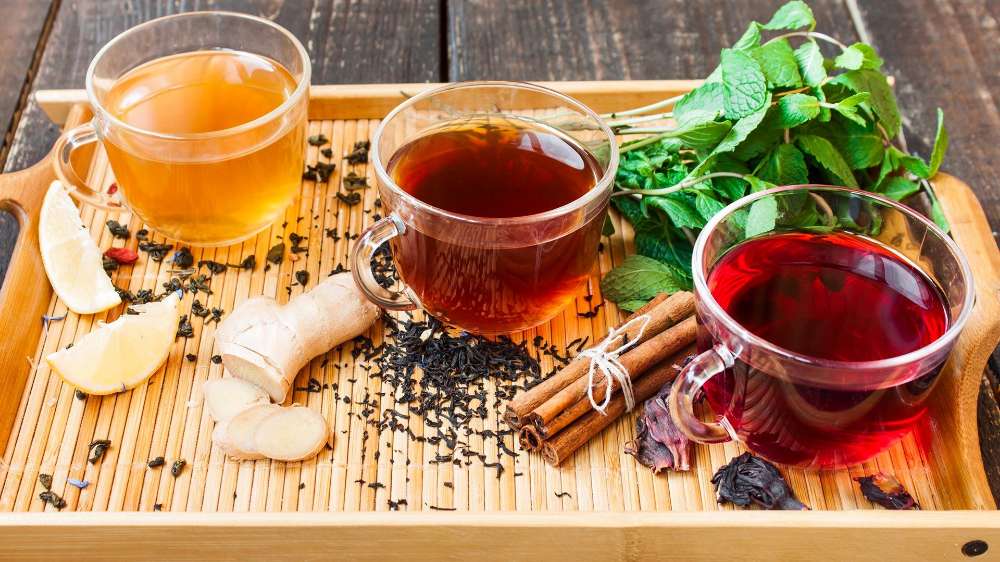 Colorful cups of tea with ginger, lemon, mint, cinnamon and loose tea leaves.